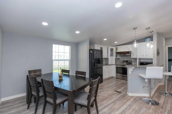 a kitchen with stainless steel appliances kitchen island granite countertop a dining table chairs and refrigerator