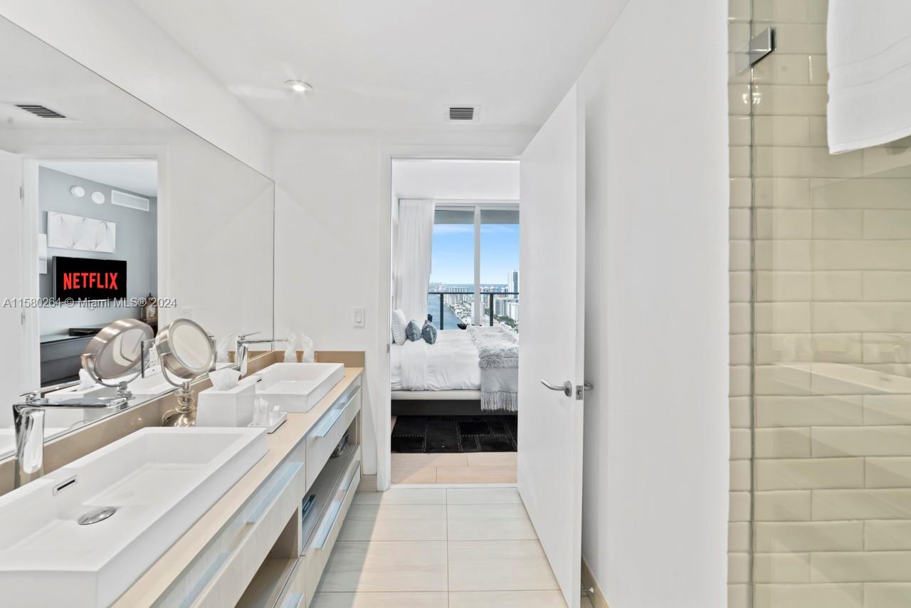 4010 South Ocean Drive, Unit R3001 Hollywood, FL 33019 - Photo 43 of 44 a en suite bathroom with a double vanity sink and a mirror