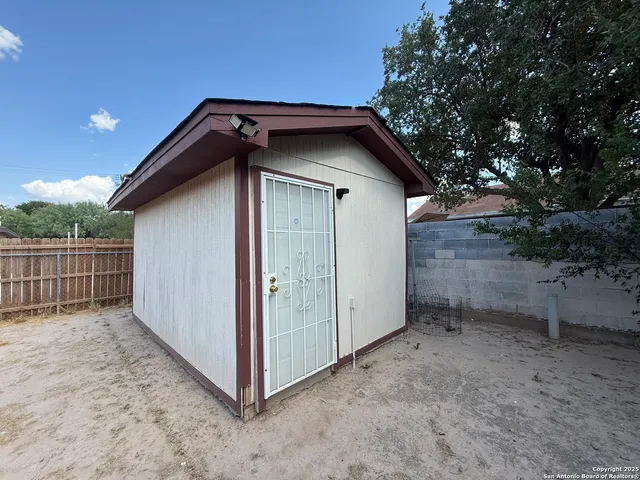 a view of a small house with a yard and wooden fence