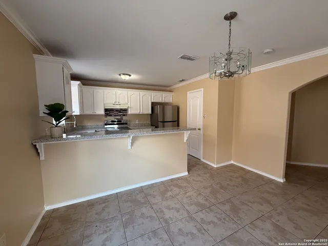 a view of kitchen with stainless steel appliances granite countertop a refrigerator a sink dishwasher a stove with white cabinets