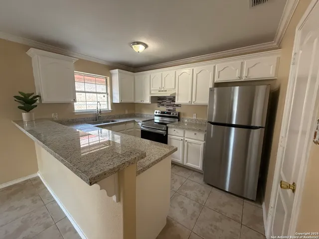 a kitchen with granite countertop a refrigerator sink stove and microwave