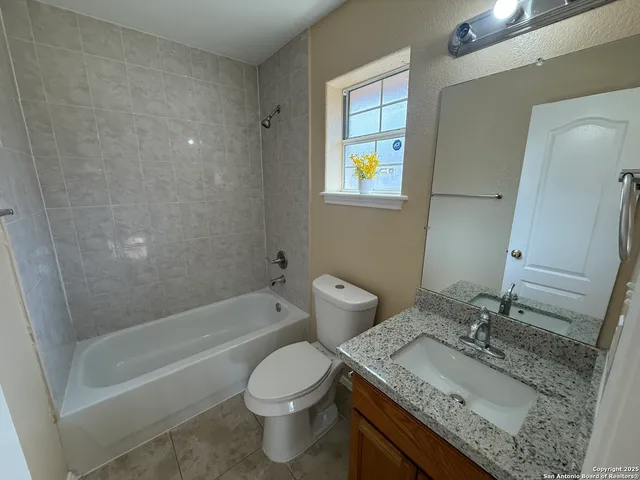 a bathroom with a granite countertop sink a toilet and bathtub