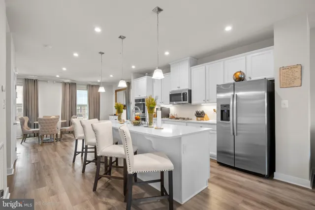 a kitchen with stainless steel appliances a dining table chairs refrigerator and sink