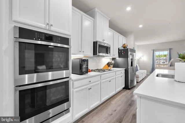 a kitchen with stainless steel appliances white cabinets a stove a sink and a microwave