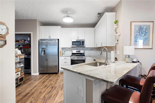 a kitchen with granite countertop a refrigerator stove top oven and sink