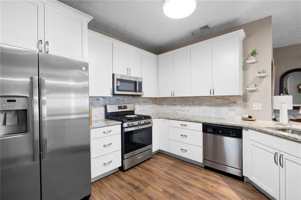 a kitchen with cabinets stainless steel appliances a sink and wooden floor