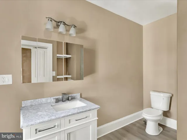 a bathroom with a granite countertop sink toilet and mirror