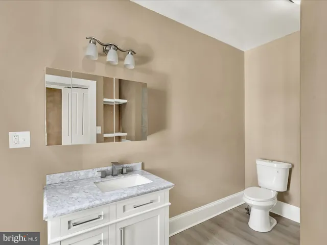 a bathroom with a granite countertop sink vanity mirror and toilet