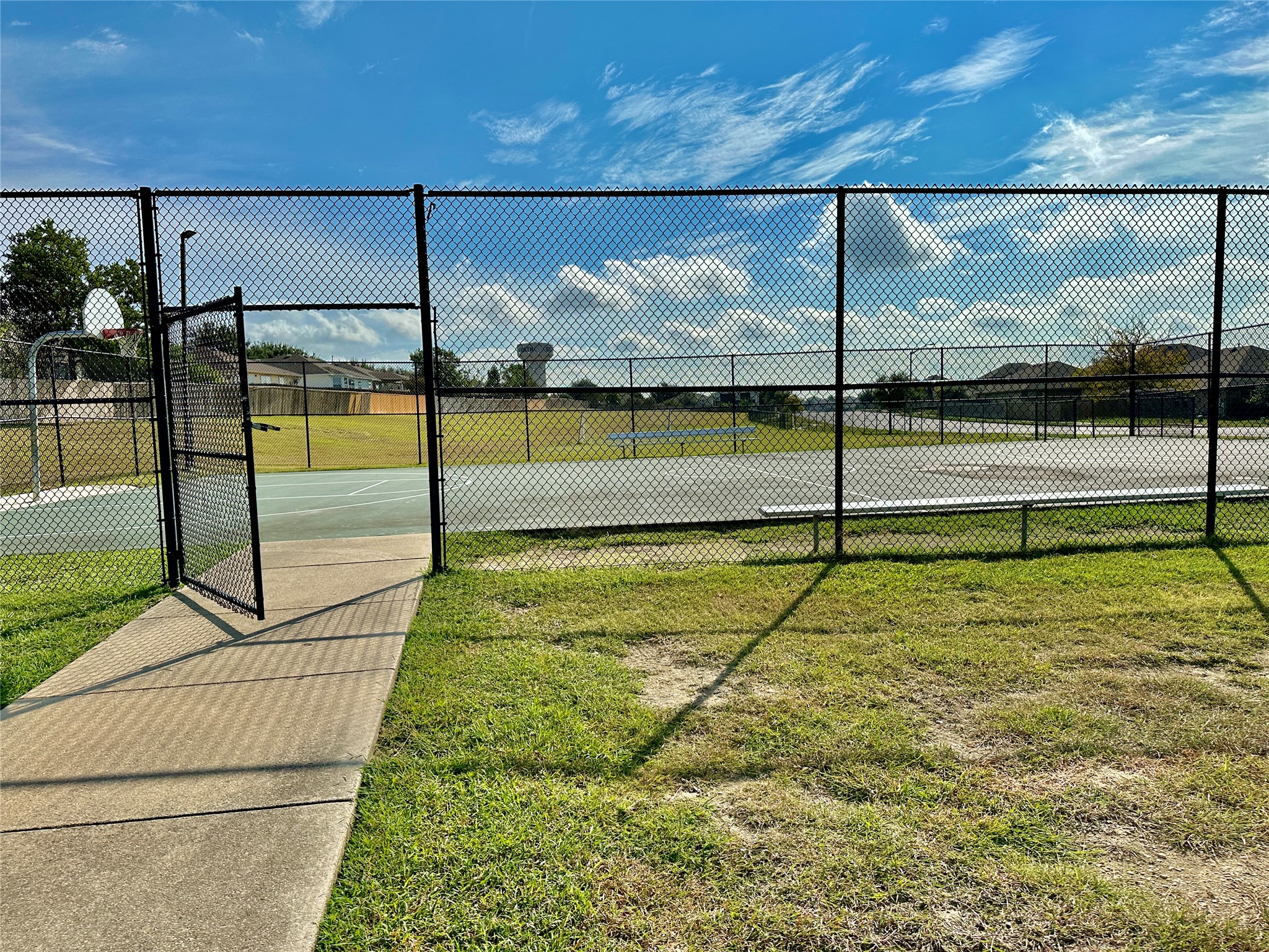 207 Dragon Ridge Road Buda, TX 78610 - Photo 34 of 38 Recreational court facility featuring chain-link fencing, concrete pathways, a basketball hoop, and painted court lines