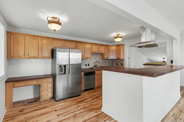 a kitchen with stainless steel appliances granite countertop a refrigerator a stove and a sink with wooden floors
