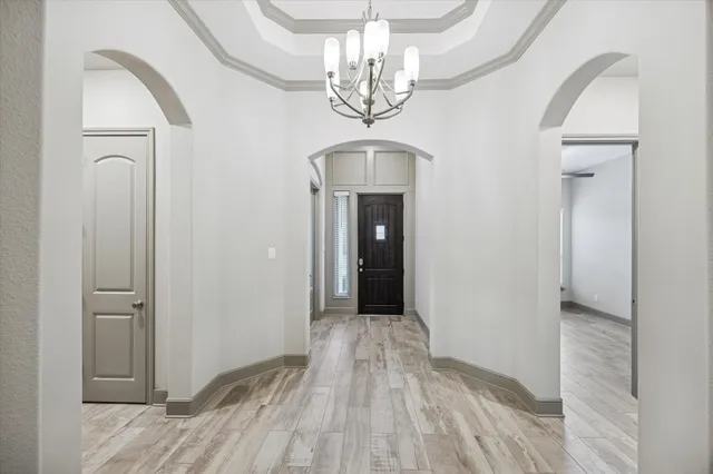 a view of a hallway with wooden floor and a chandelier