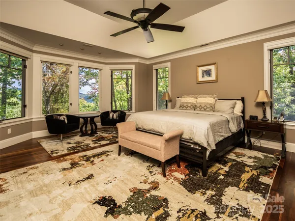 a spacious bedroom with a bed a table and chair with the view of living room