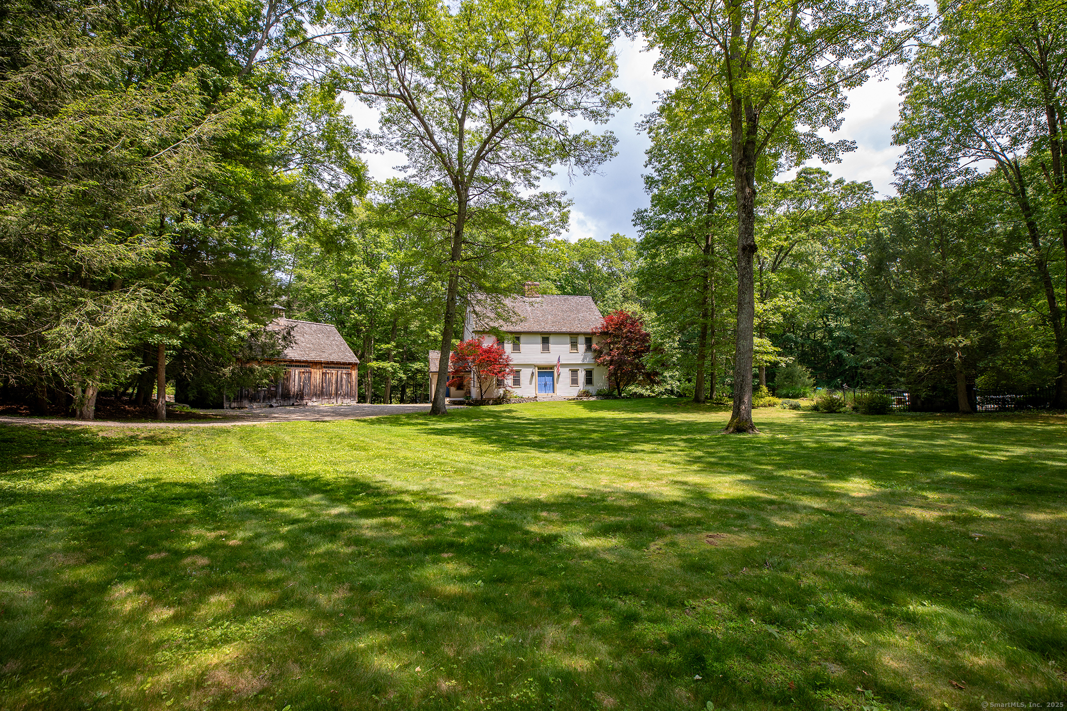 a view of a big house with a big yard and large trees