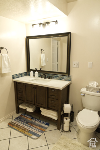 588 Raspberry Patch Road Garden City, UT 84028 - Photo 29 of 74 Bathroom featuring light tile patterned floors, vanity, a textured ceiling, and tasteful backsplash