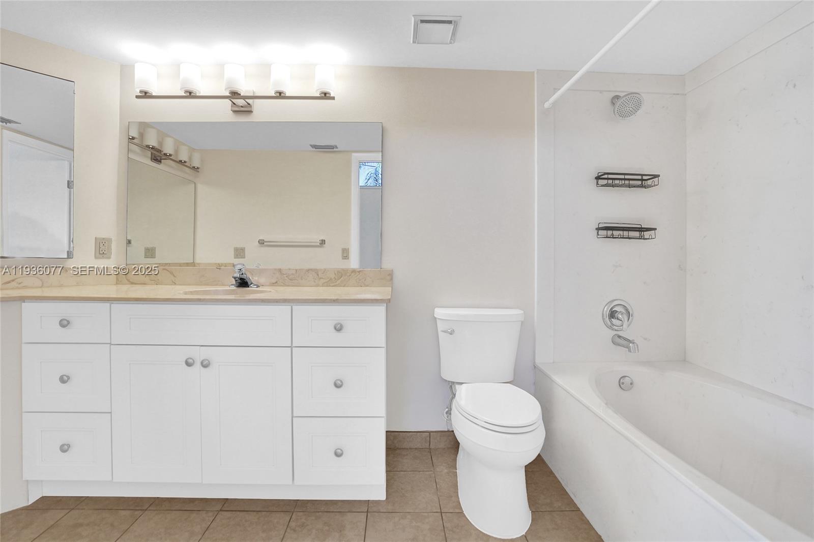 9569 Boca Gardens Parkway, Unit B Boca Raton, FL 33496 - Photo 14 of 40 a bathroom with a toilet a sink a mirror and a bathtub