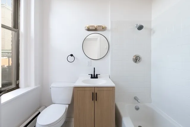 a bathroom with a toilet a sink a mirror and a window