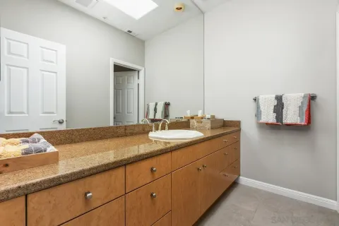 a bathroom with a granite countertop toilet a sink and a mirror