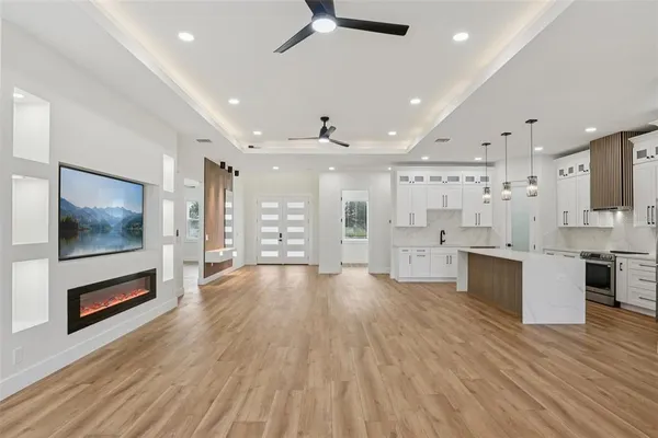 a large white kitchen with a stove oven a sink dishwasher and a refrigerator with wooden floor