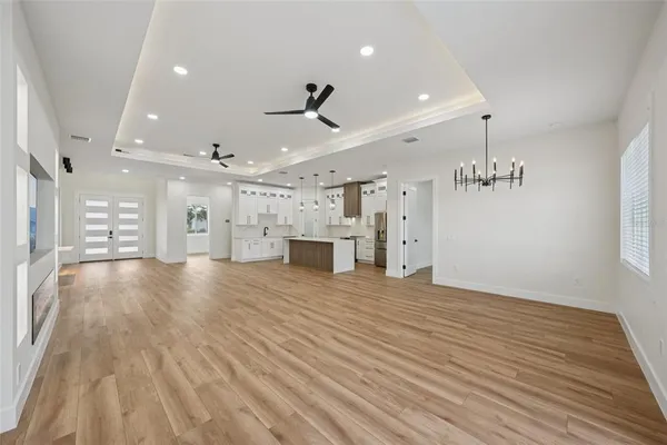 a large white kitchen with a stove a sink dishwasher and a refrigerator with wooden floor