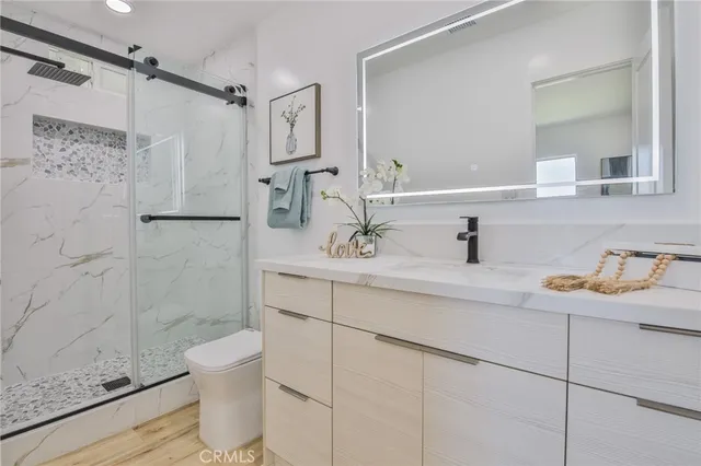 a bathroom with a granite countertop sink a toilet and shower
