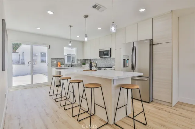 a kitchen with stainless steel appliances kitchen island a refrigerator and a wooden cabinets