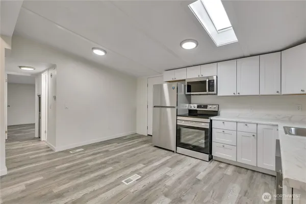 a kitchen with granite countertop white cabinets stainless steel appliances and a window