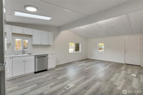 a view of an empty room with window and wooden floor