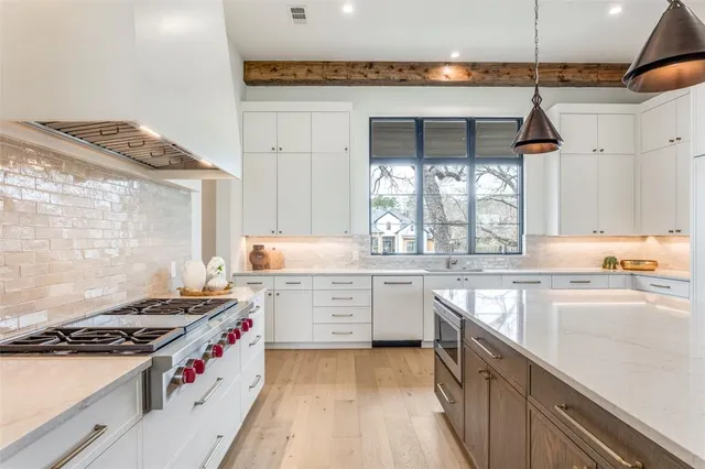 a kitchen with a stove a sink a window and cabinets