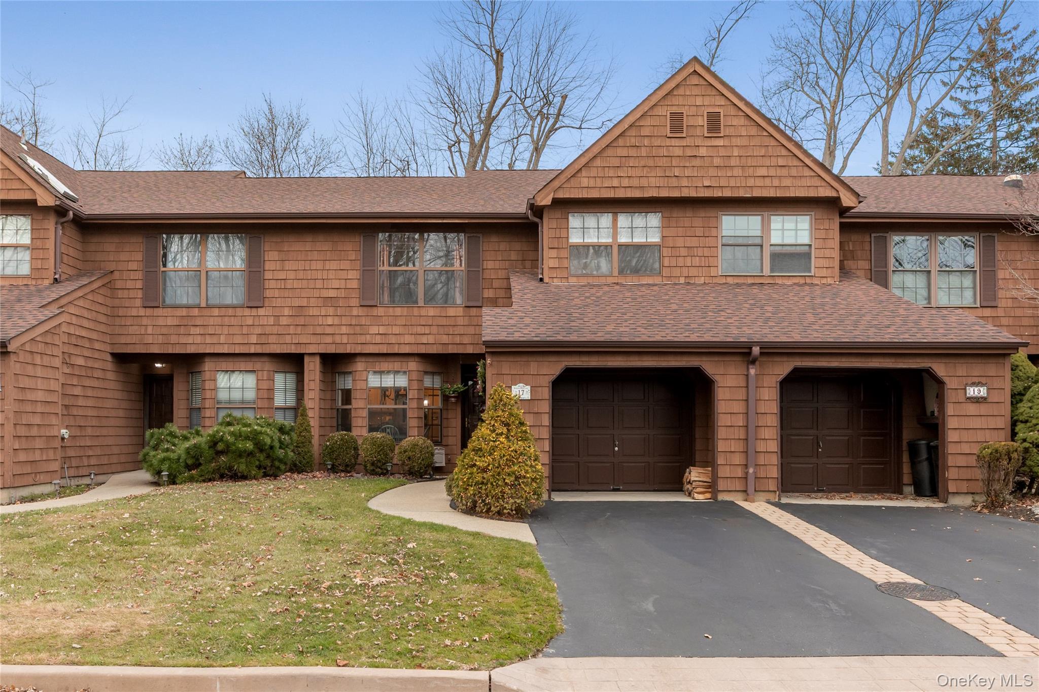 View of front facade featuring a shingled roof, driveway, a garage, and a front lawn