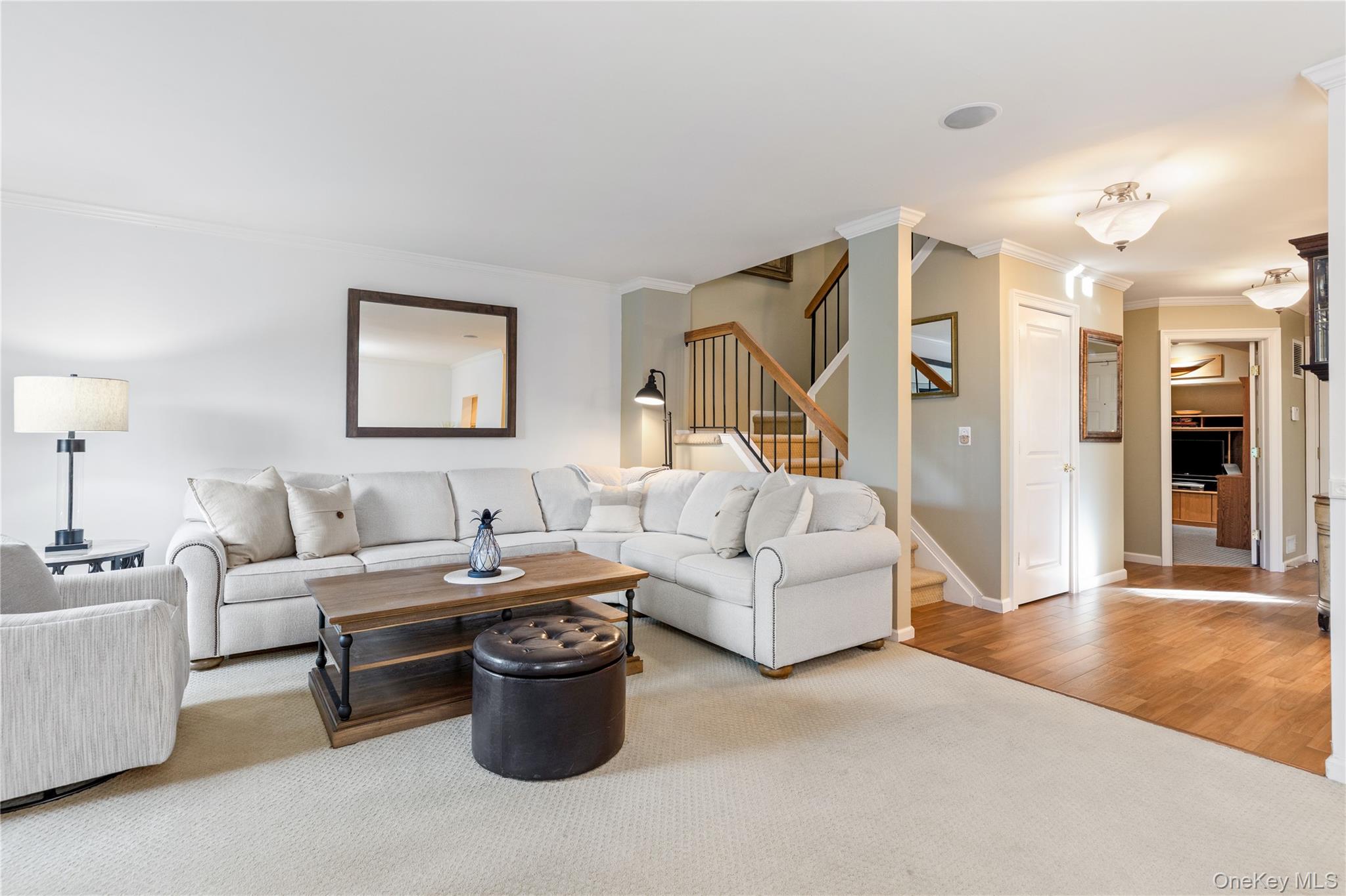 17 Sutton Place Islip, NY 11751 - Photo 11 of 32 Living area with crown molding, stairs, light colored carpet, and light wood-style floors