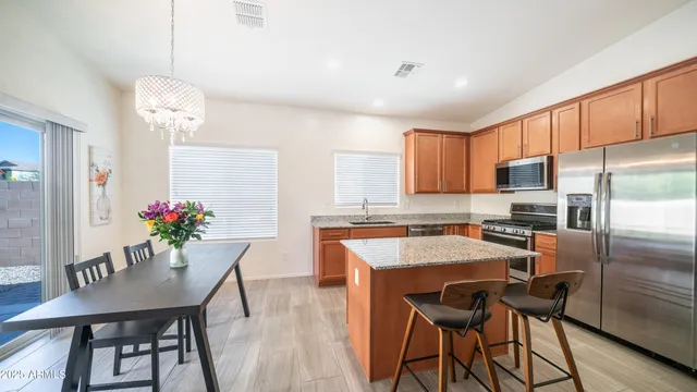 a kitchen with granite countertop kitchen island stainless steel appliances cabinets dining table and chairs