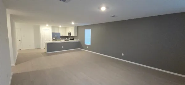a view of kitchen and empty room with wooden floor