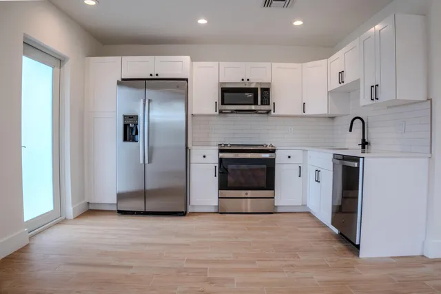 a kitchen with stainless steel appliances kitchen island granite countertop a refrigerator and a sink