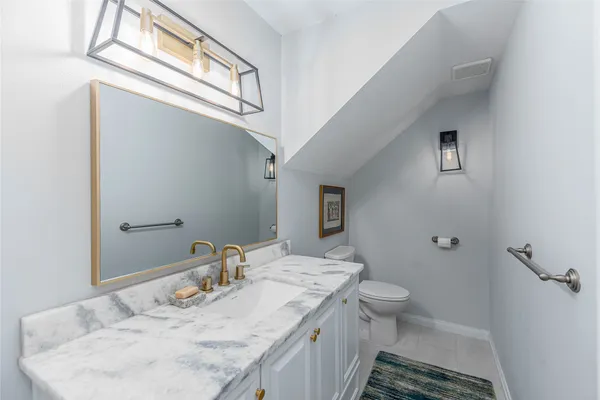 a bathroom with a granite countertop sink a toilet and a mirror