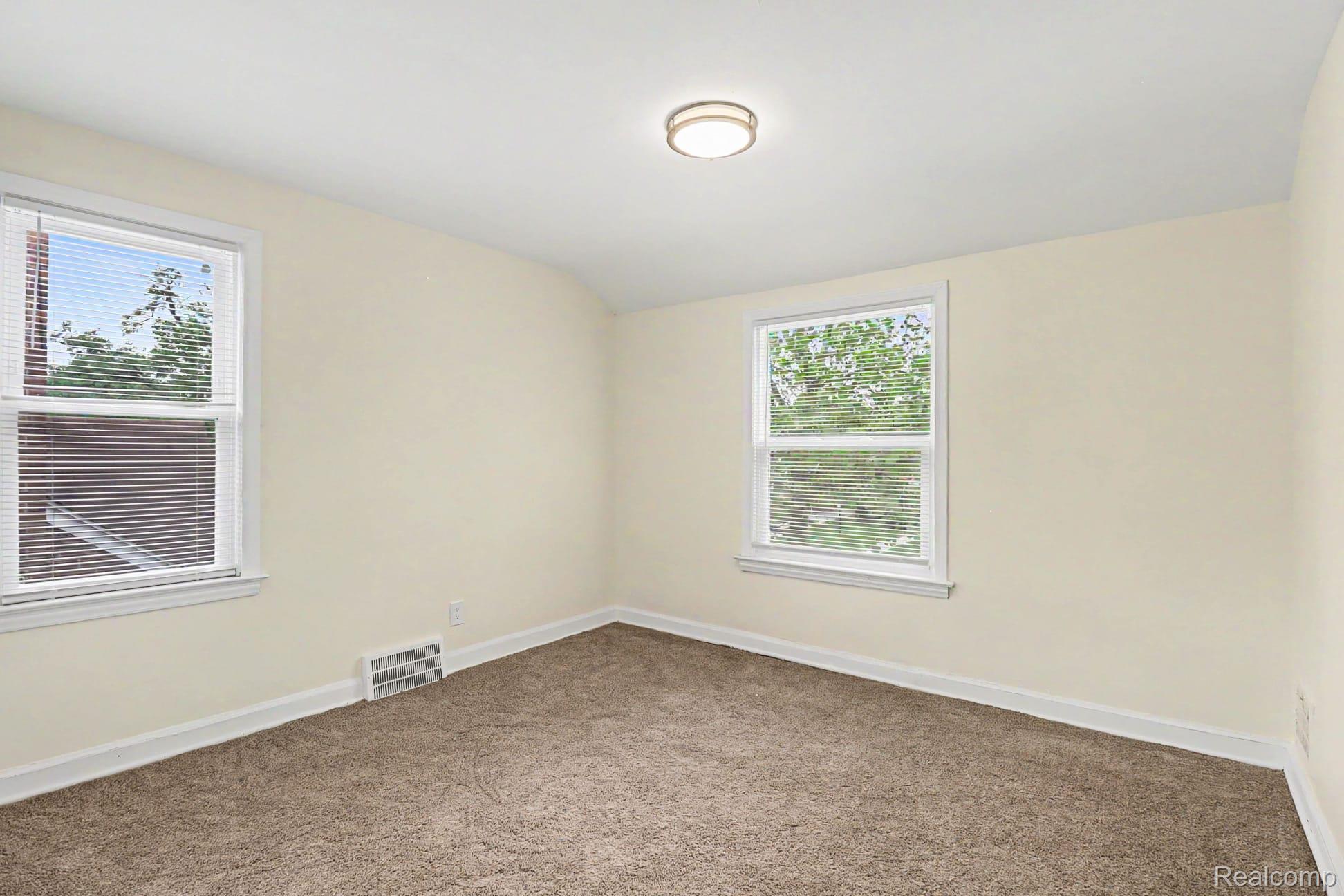 16682 Robson Street Detroit, MI 48235 - Photo 16 of 19 Neutral-toned room featuring two sash windows with horizontal blinds, light beige walls, and brown carpet flooring