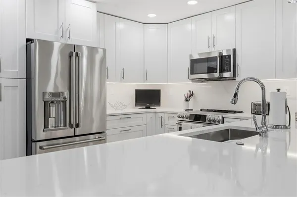 a kitchen with stainless steel appliances kitchen island granite countertop a refrigerator and a stove top oven