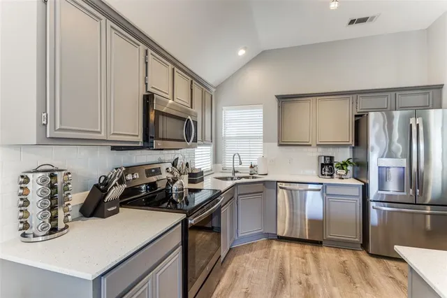 a kitchen with stainless steel appliances granite countertop a sink a stove a refrigerator and cabinets