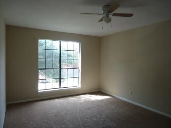 an empty room with windows and fan