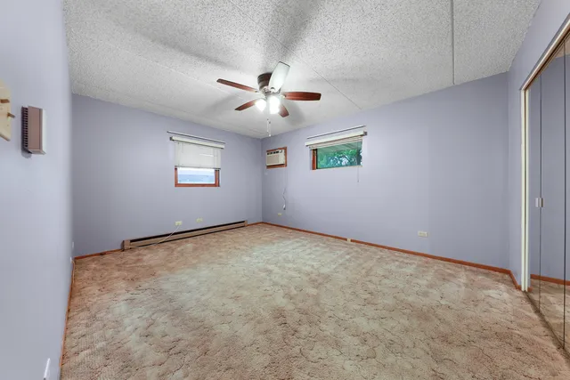 an empty room with windows and ceiling fan