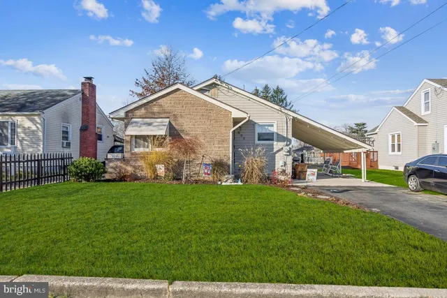 a view of a white house next to a yard with big trees