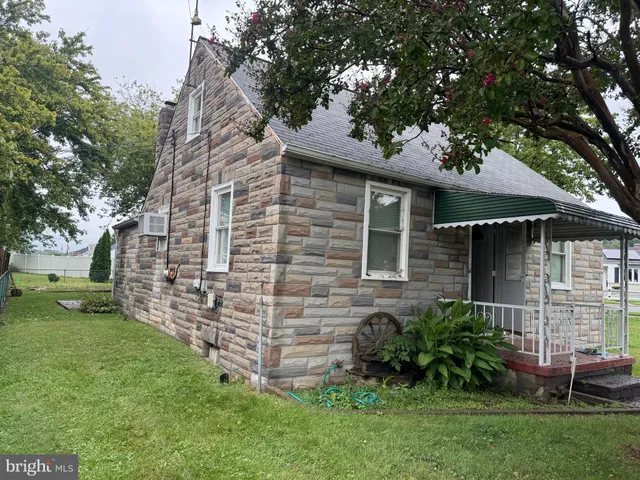 a view of a brick house with a yard potted plants and large tree