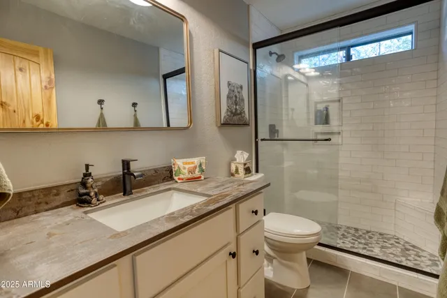 a bathroom with a granite countertop sink a toilet a mirror and shower