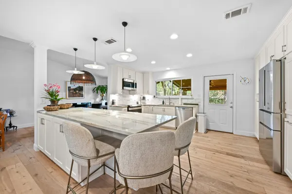 a kitchen with stainless steel appliances kitchen island granite countertop a stove and a wooden floors