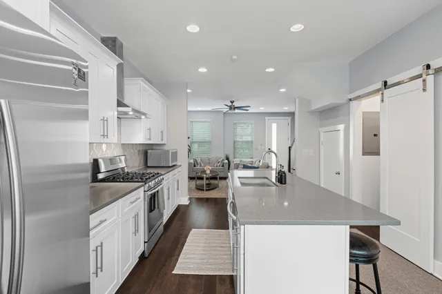 a large kitchen with kitchen island a stove a sink a refrigerator and a dining table with wooden floor