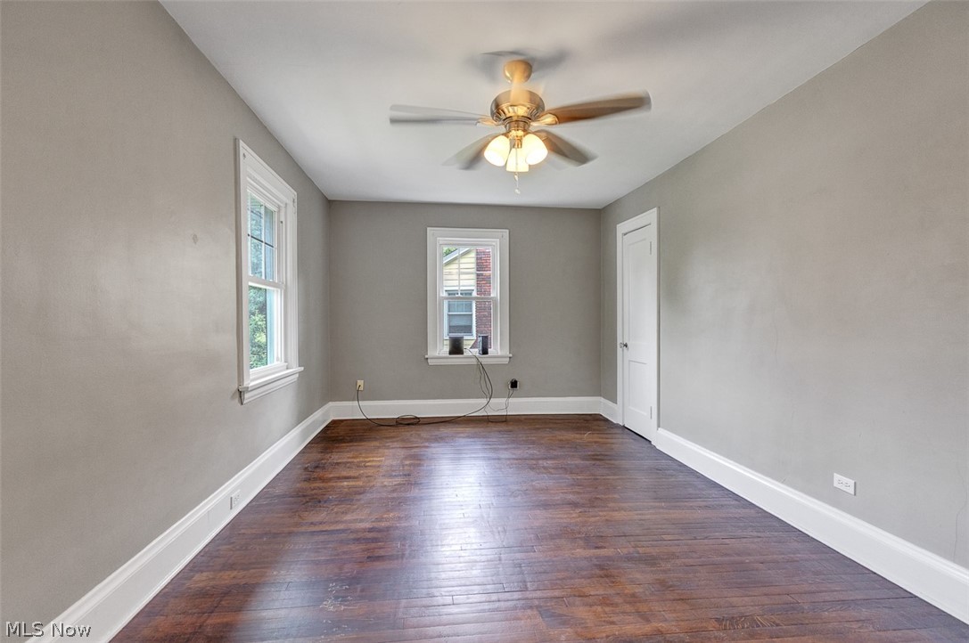 2972 Yorkshire Road Cleveland Heights, OH 44118 - Photo 27 of 44 Spacious room featuring wood-finish flooring, two windows with white trim, a ceiling fan with integrated lighting, and a white door