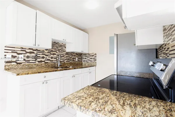 a view of a kitchen with kitchen island granite countertop a sink and a stove