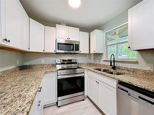 a kitchen with granite countertop white cabinets and white appliances