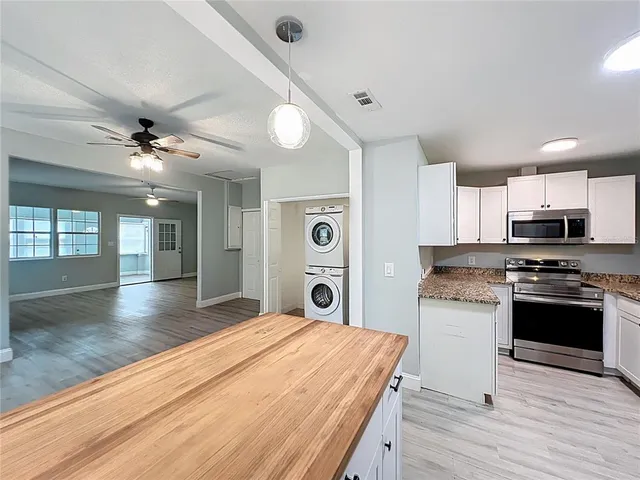 a kitchen with granite countertop white cabinets and a wooden floor