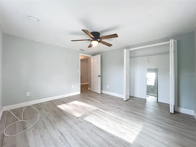 a view of empty room with wooden floor and fan