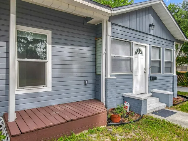 a view of brick house with a large window and potted plants